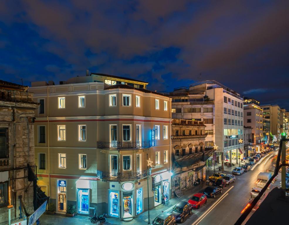 una calle de la ciudad por la noche con edificios y coches en Lotus Inn, en Atenas