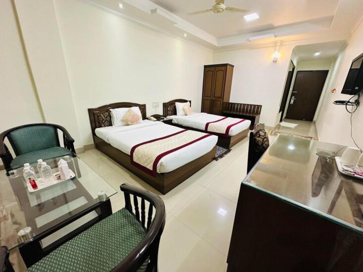 a hotel room with two beds and a table and chairs at Bodhgaya Regency Hotel in Bodh Gaya