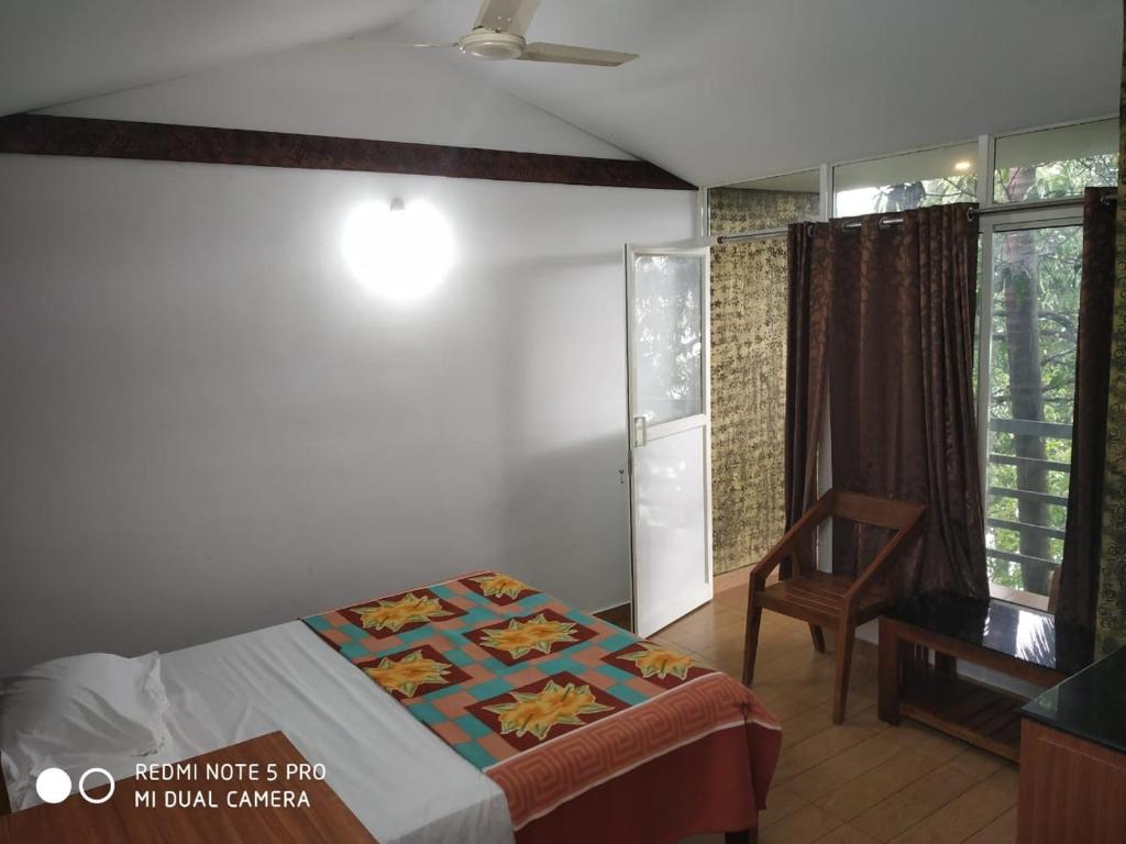 a bedroom with a bed and a chair and a window at Peninsular wood Resort in Thattakād