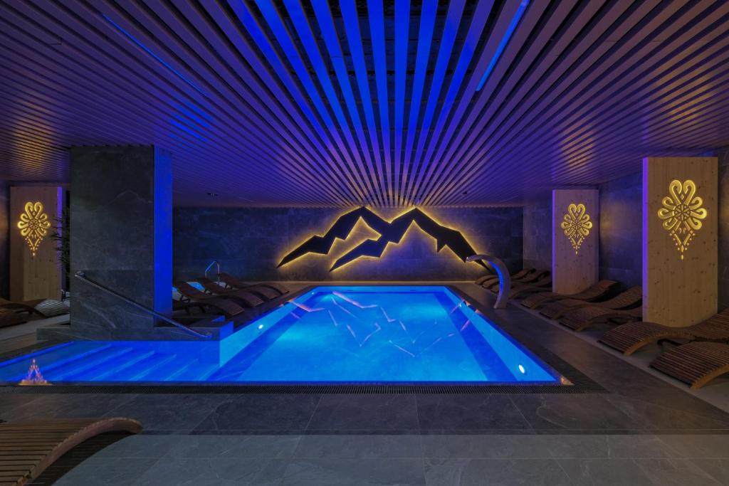 a swimming pool in a room with purple lighting at Black Mountain Residence & SPA, Odkryj-Białkę in Białka Tatrzańska