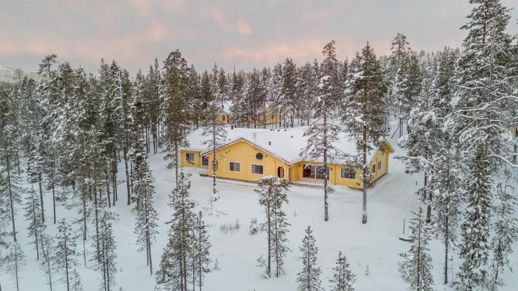 a yellow cabin in the snow in a forest at Sallainen Panvillage in Salla