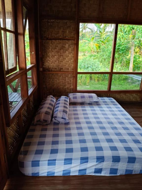 a large bed in a room with two windows at Konbayan Forest Stay in Bayan