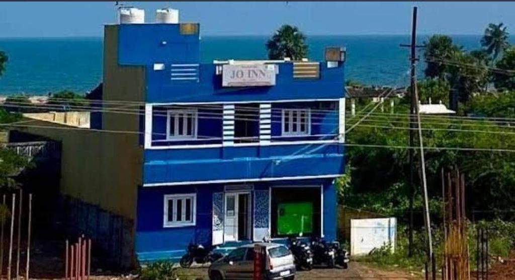 a blue building with a car parked in front of it at Jo Inn Beach View Guest House in Kuilapayam