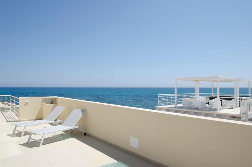 a balcony with chairs and the ocean on a boat at Cicirìa - Private Seafront Suites in Avola