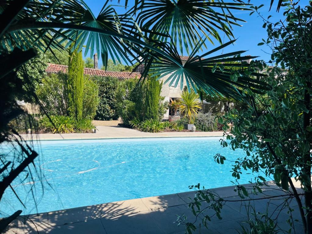 a swimming pool in a yard with trees at Le Logis de la Soloire 3 étoiles in Nercillac