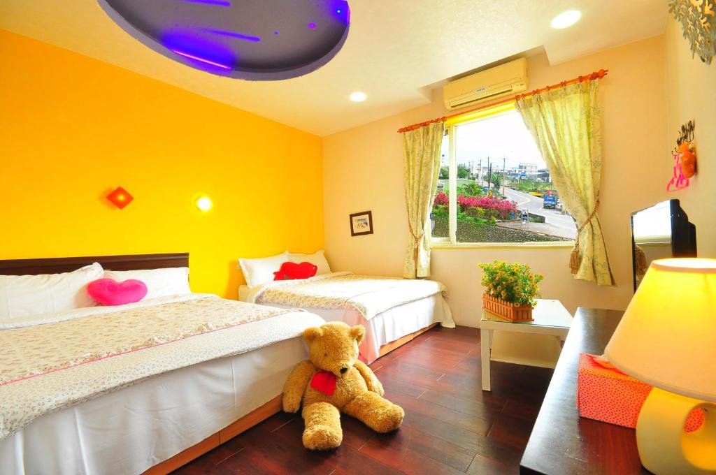 um quarto com duas camas e um urso de peluche sentado no chão em Smile Orange Homestay em Dongshan