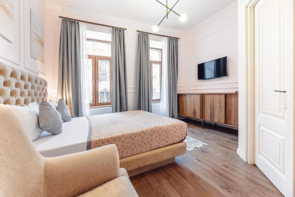 a bedroom with a bed and a couch and a tv at Boutique Hotel Manufactura in Tbilisi City