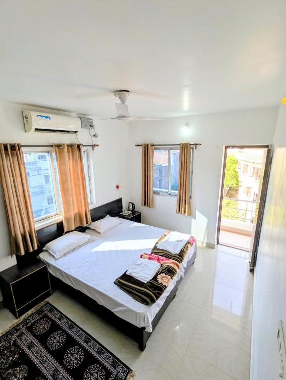 a bedroom with a bed in a room with windows at Dwarka Home Stay in Bodh Gaya