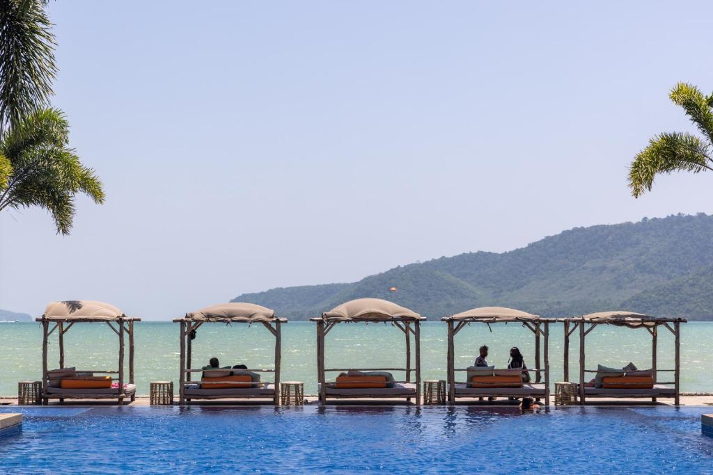 a resort swimming pool with people sitting on the beds at Selina Serenity Rawai Phuket in Rawai Beach