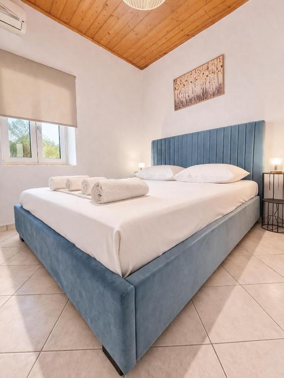 a large bed in a bedroom with a blue headboard at Nature's Nook Paxos in Vlachopoulátika