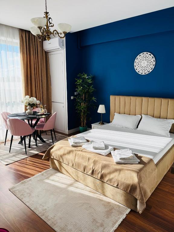 a bedroom with a large bed and a blue wall at Luxury Studio Mamaia Nord in Mamaia Sat/Năvodari
