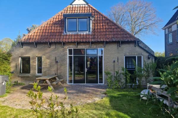 a small brick house with a picnic table in front of it at Nes-Tijd in Nes