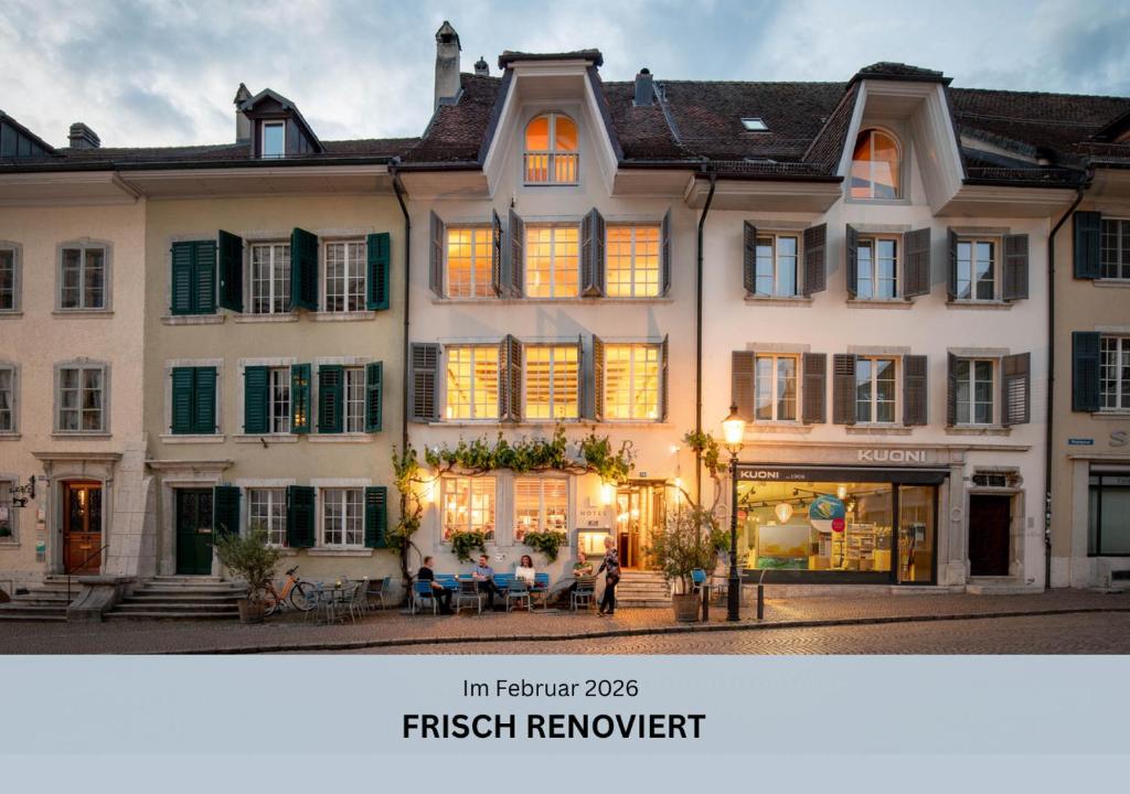a large white house with people sitting in front of it at Baseltor Hotel & Restaurant in Solothurn