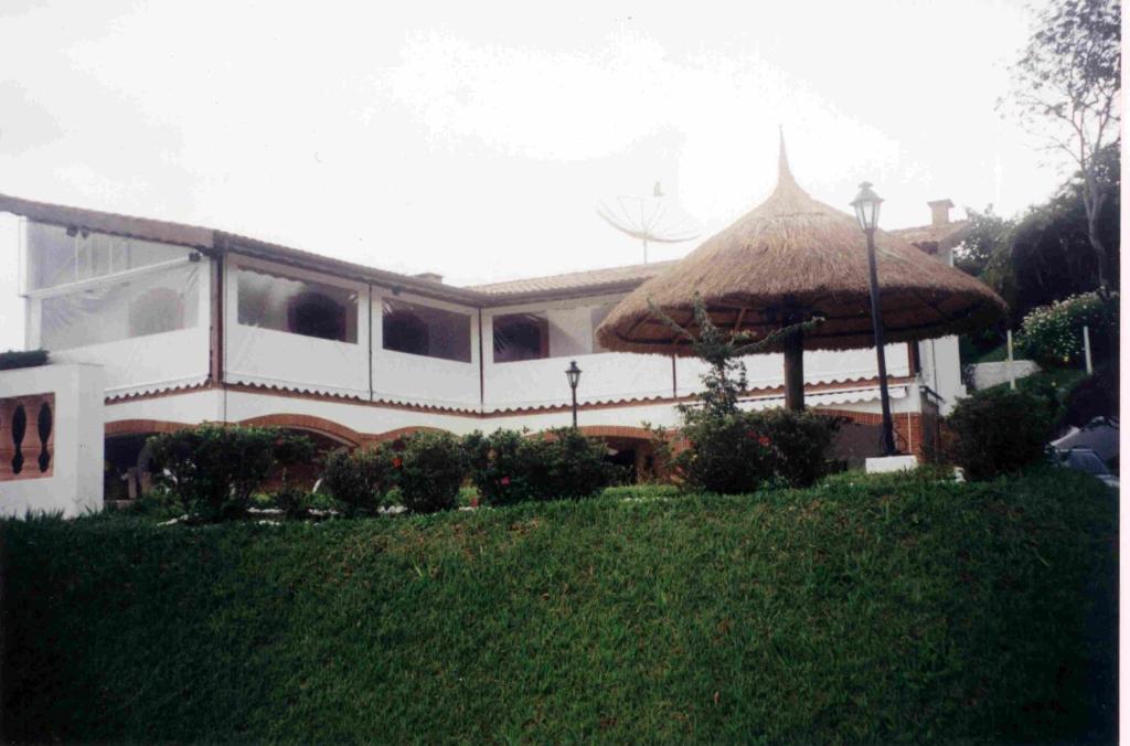 a large house with a large straw umbrella at Atibaia - Casa de Campo in Atibaia