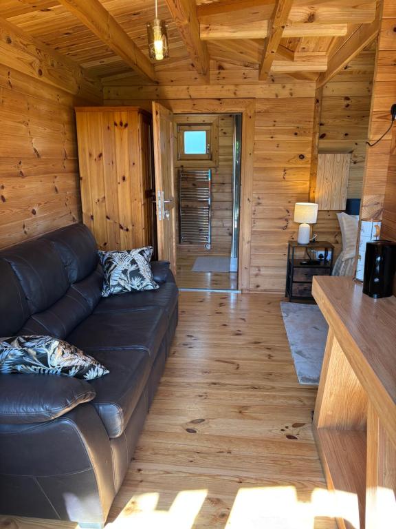 a living room with a leather couch in a log cabin at Trelew Farm Log Cabin in Penzance