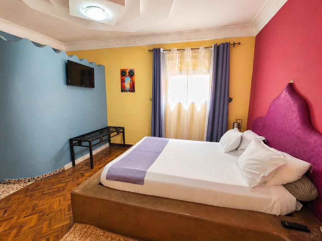 a bedroom with a large bed with colorful walls at Hôtel la medina in Antananarivo
