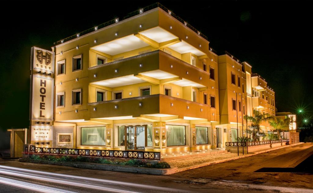 Un grand bâtiment jaune avec des lumières allumées la nuit dans l'établissement BHB Hotel, à Mandurie