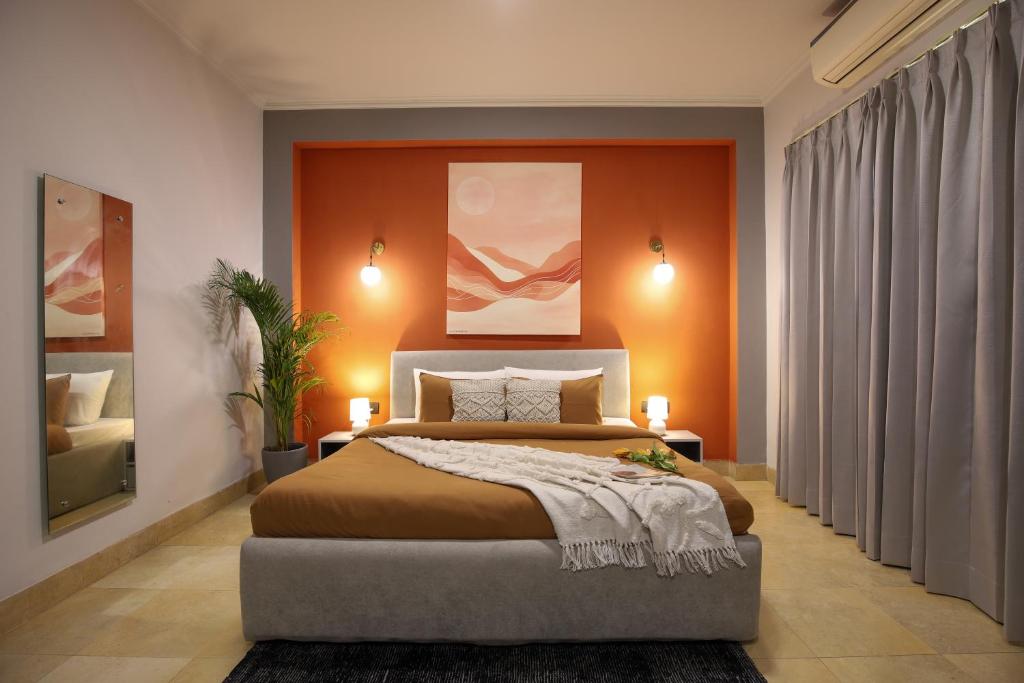 a bedroom with a large bed with an orange wall at Studio Serviced Apartments near Fortis Hospital in Gurgaon