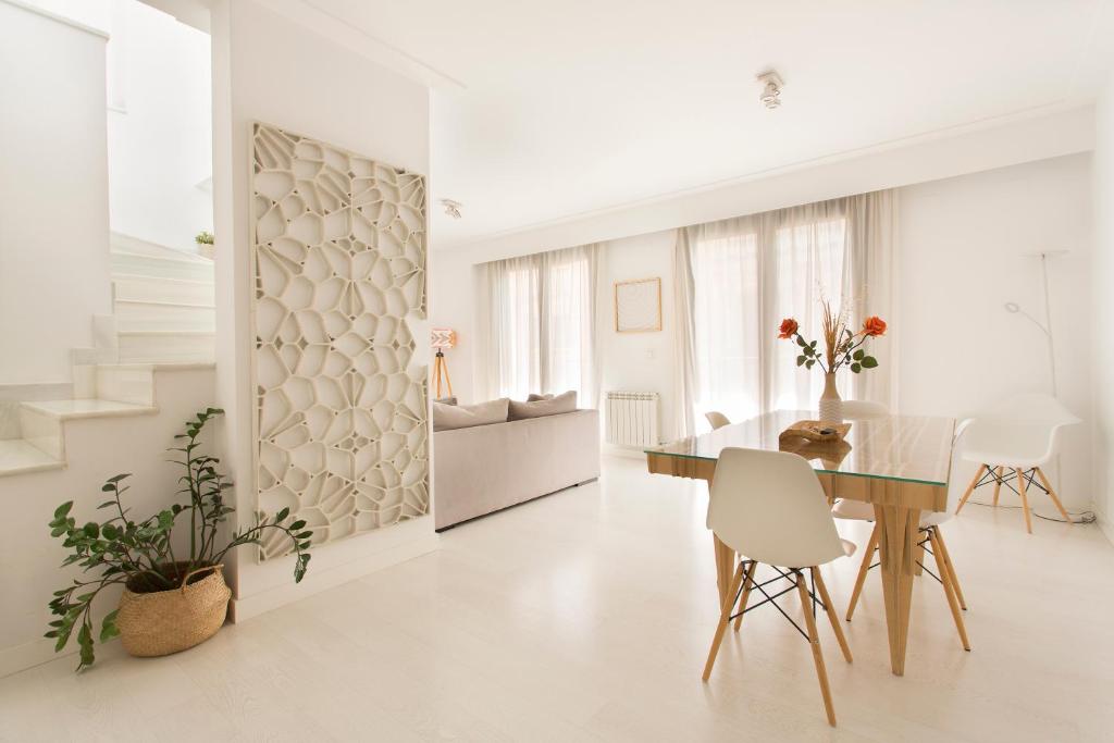 a white dining room with a glass table and white chairs at Realejo Horizon por Miwa Studio in Granada