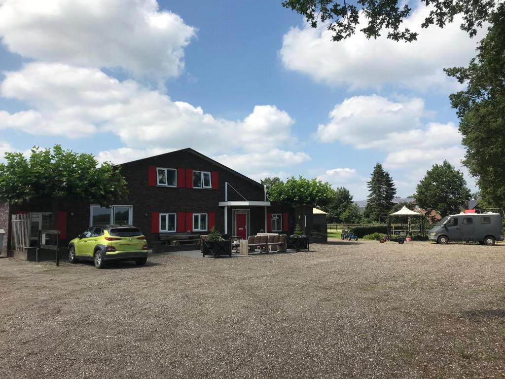 a red house with a car parked in a parking lot at De Peelrand Hoeve in Venhorst