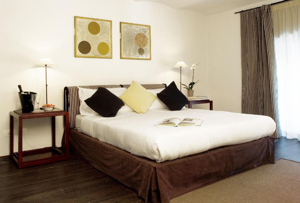 una camera da letto con letto, lenzuola e cuscini bianchi di Margutta Mews a Roma