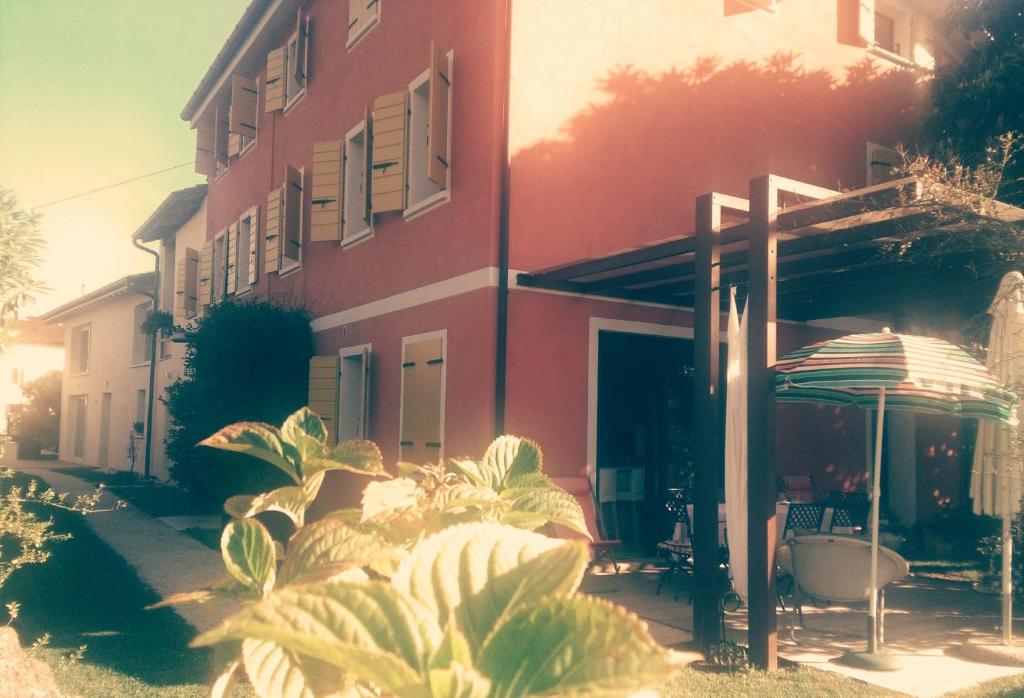 ein rotes Gebäude mit einem Regenschirm und Pflanzen davor in der Unterkunft B&B Terre Di Bea in Pederobba