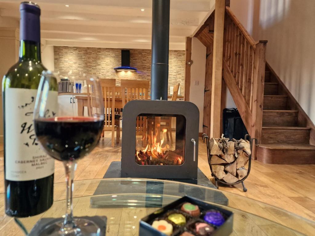 a glass of wine and a bottle of red wine and a glass of wineearcher at Ponycob hot tub 2 bed ensuite in Llwyn-Dafydd