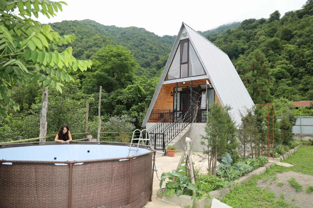 a woman sitting in a tub in front of a house at LUNEA cottage in Machakhlispiri
