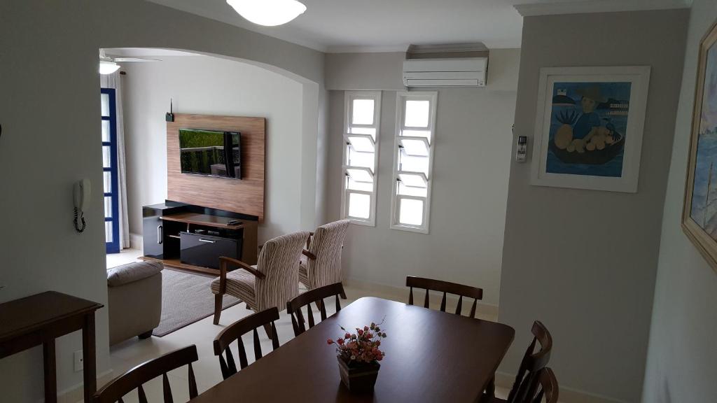 a dining room with a table and chairs and a television at Acarau Unidade 15 in Ubatuba