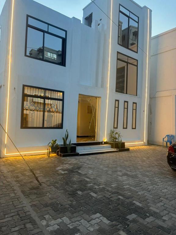 a white building with a car parked in front of it at Gekamo Suites in Dar es Salaam
