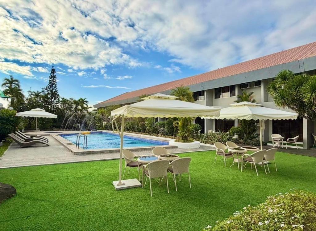 a yard with chairs and umbrellas and a pool at Maharajah Hotel Angeles City in Angeles