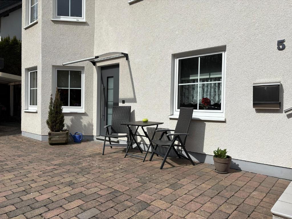 a patio with a table and chairs in front of a house at Ferienwohnung Waldblick in Brilon