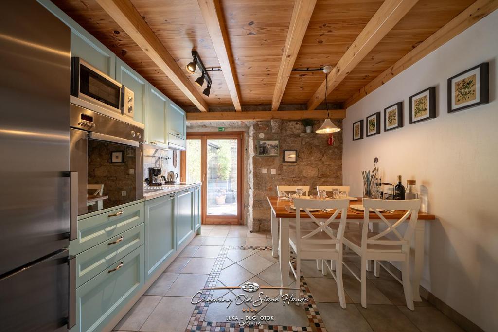 a kitchen with a wooden ceiling and a table with chairs at Charming old stone house in Sali