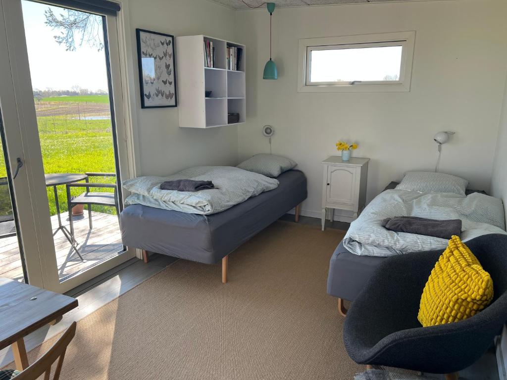ein Zimmer mit zwei Betten, einem Tisch und einem Fenster in der Unterkunft Almegården in Græsted