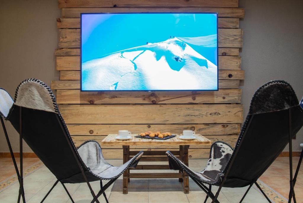 a living room with two chairs and a tv on a wall at Hotel Austria by Pierre & Vacances in Soldeu