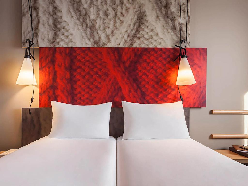 two beds in a room with two lights above them at ibis Sens in Sens