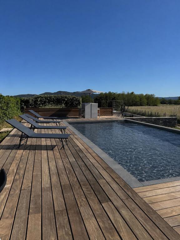 a swimming pool with a wooden deck and a pool at Mini Villa avec piscine privée in Porto-Vecchio