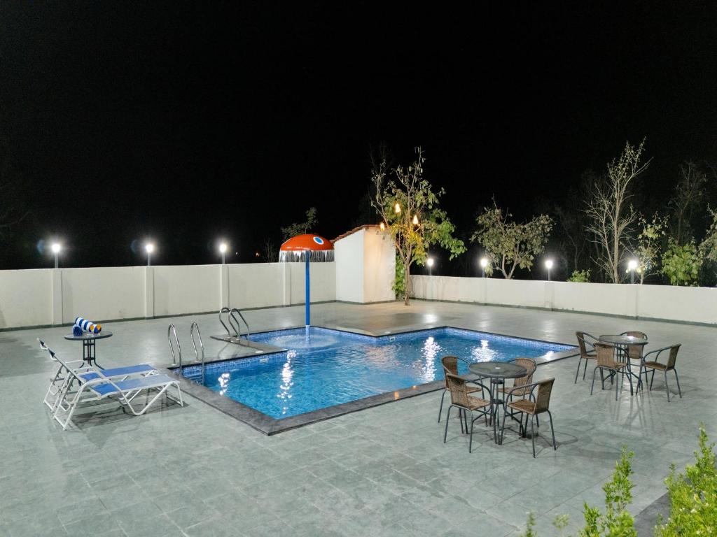 a swimming pool at night with tables and chairs at Palette Hotel Orient Greenz by CheckIn, Pench in Khawāsa