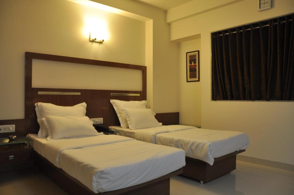 a bedroom with two beds and a window at Hotel Happiness in Surat