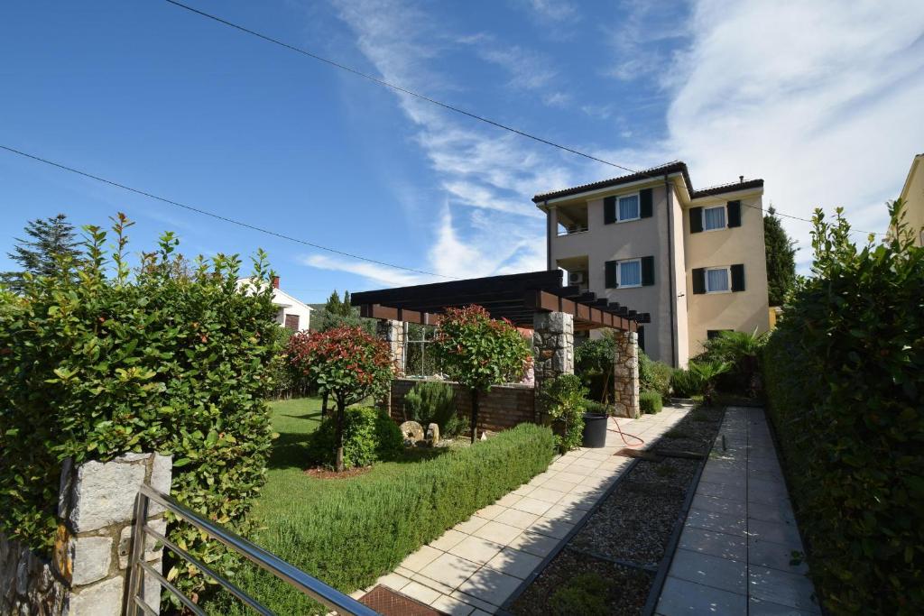 a house with a garden in front of a building at Apartments Ravlic in Punat