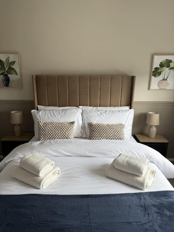 a large white bed with two white pillows on it at Knowes Apartment in Duntocher