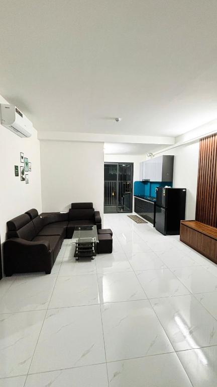a living room with a black couch and a kitchen at Chung cư Tràng Duệ in An Dương