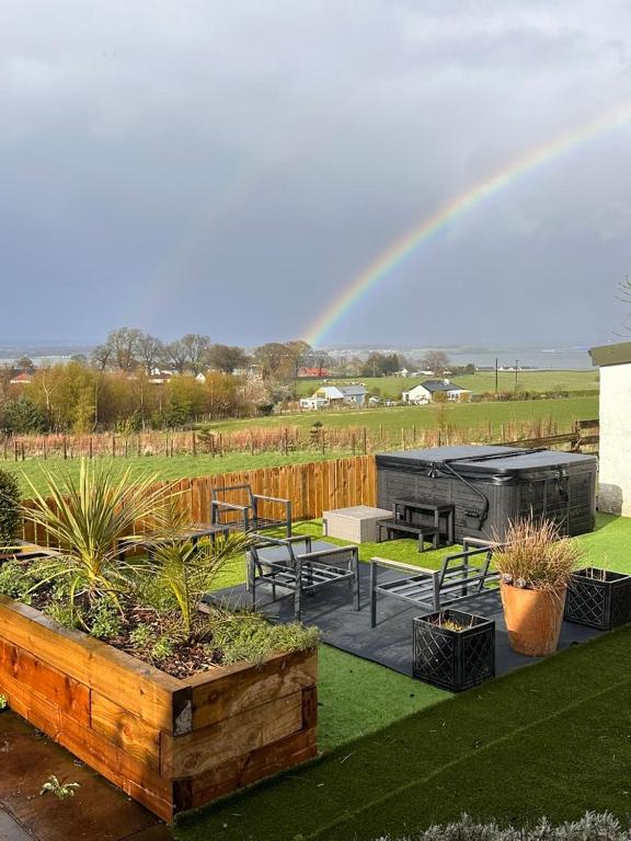 a rainbow over a garden with benches and tables at Hot tub Retreat, Linlithgow in Linlithgow