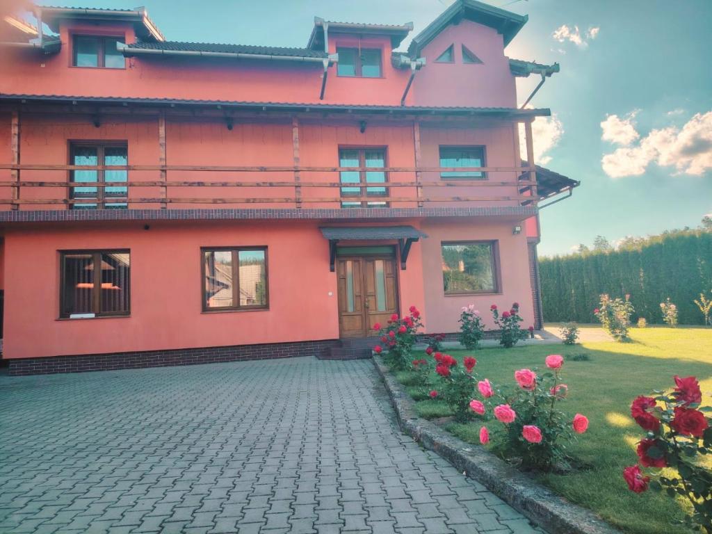 a pink house with flowers in front of it at Pensiunea Floro in Întorsura Buzăului