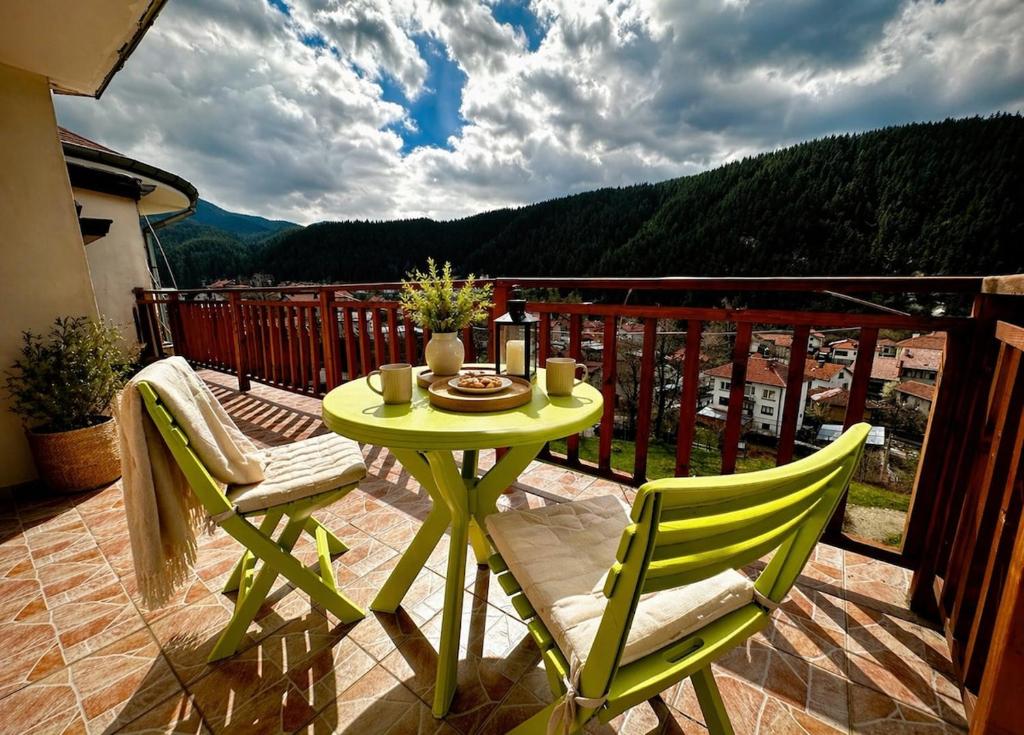 a green table and chairs on a balcony at Panoramic Cozy Apartment in Beli Iskar