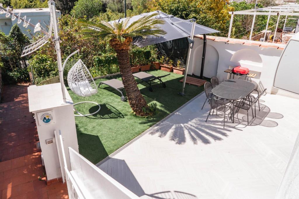 a patio with a table and chairs and a palm tree at La Casetta di Carol in Capri