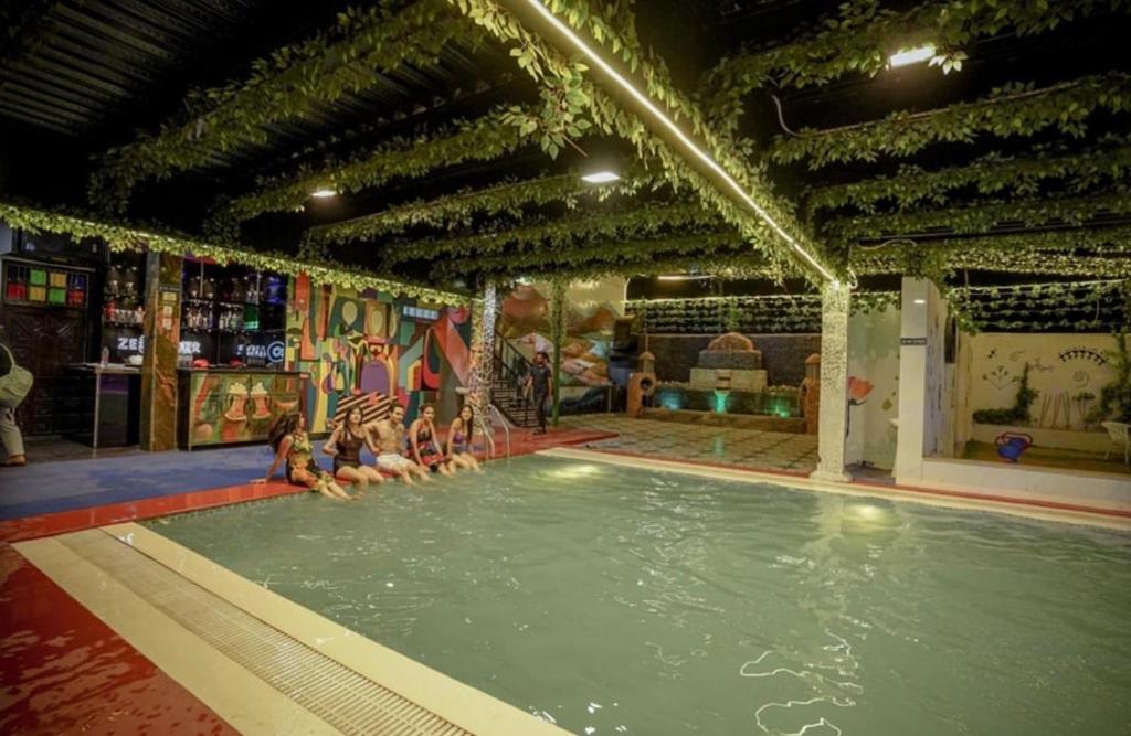 a group of people sitting in a swimming pool at Zero Amer Royal Farm Stay in Jaipur