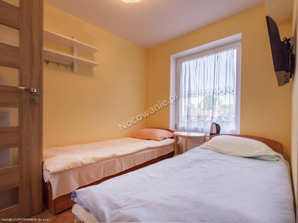 two beds in a room with a window at Pokój 2-osobowy in Węgorzewo