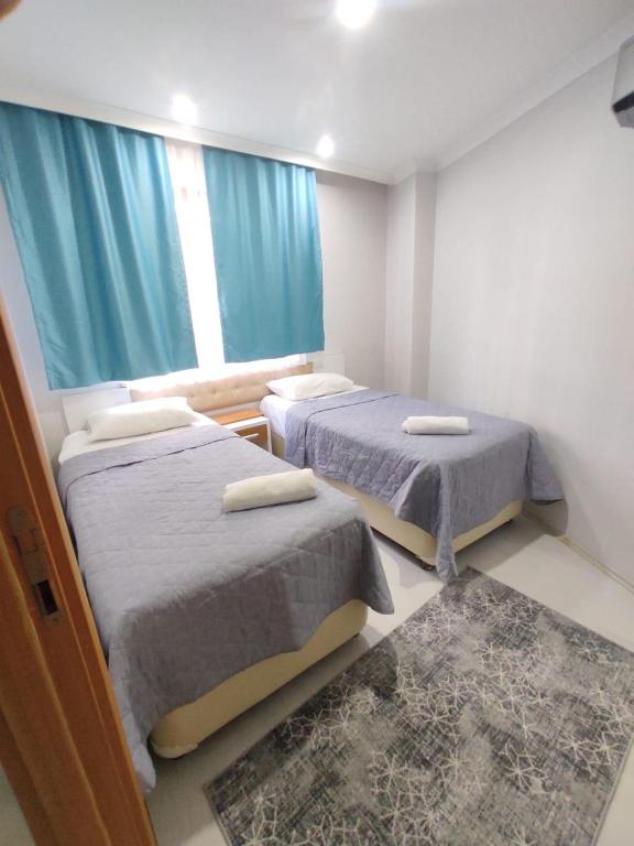 a room with two beds and a window with blue curtains at Can Residence in Trabzon