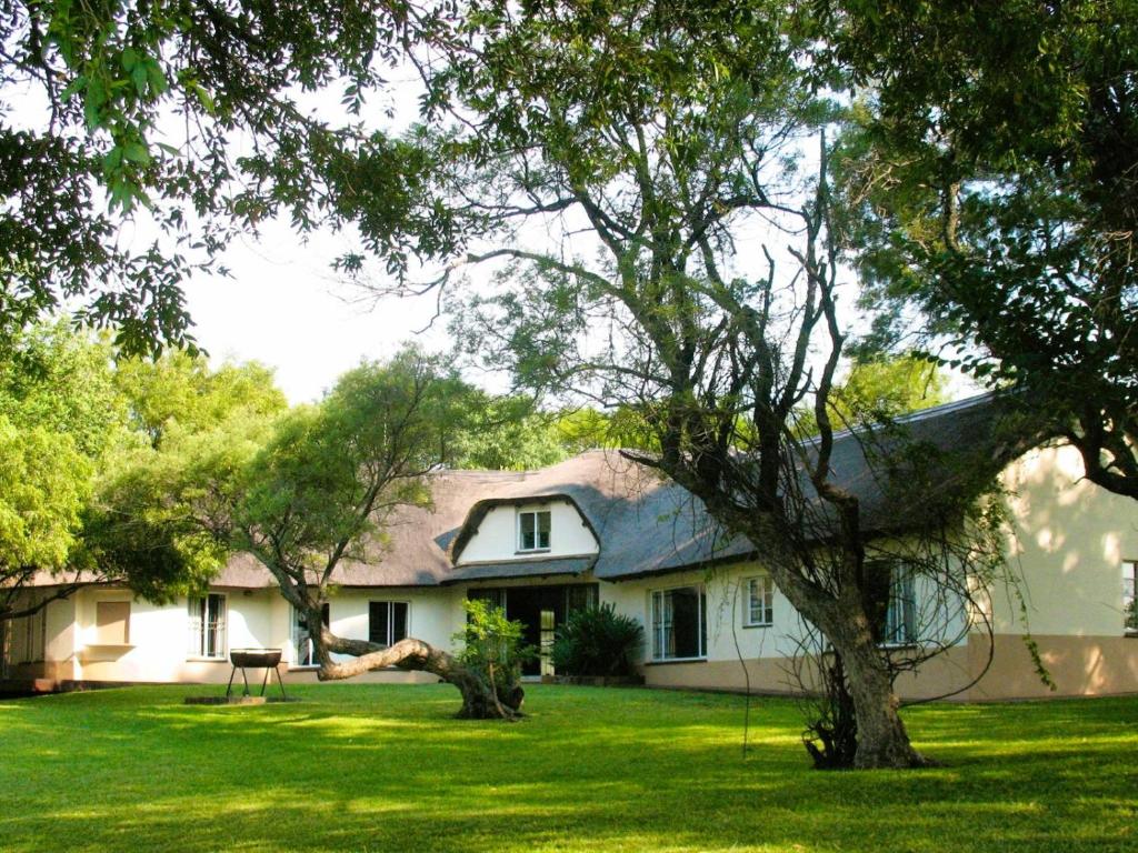 a white house with a tree in the yard at Jimmy's Place in Dinokeng Game Reserve